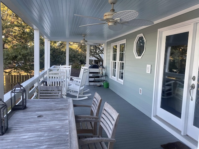 wooden terrace with outdoor dining space, fence, and ceiling fan