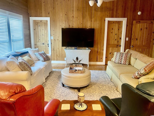 living room featuring hardwood / wood-style floors, wooden walls, and ceiling fan