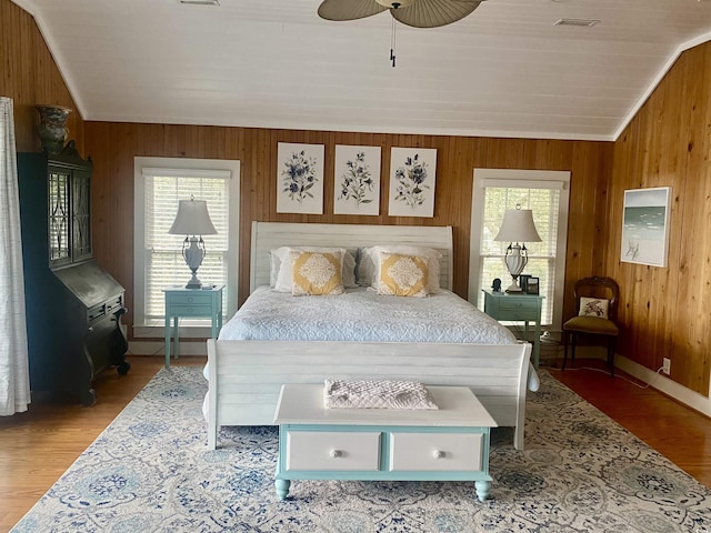 bedroom with multiple windows, ceiling fan, and wood walls