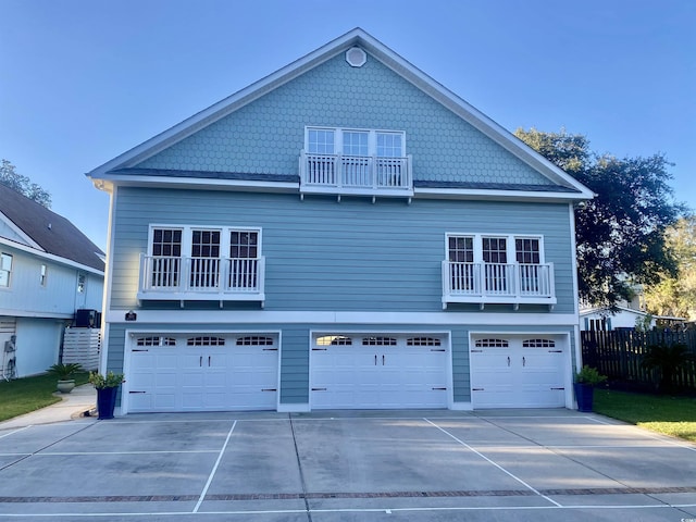 exterior space with a balcony, an attached garage, fence, and driveway