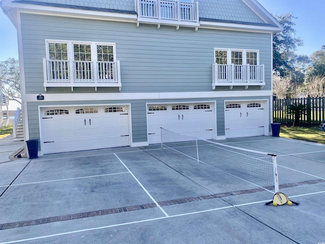 garage with concrete driveway and fence