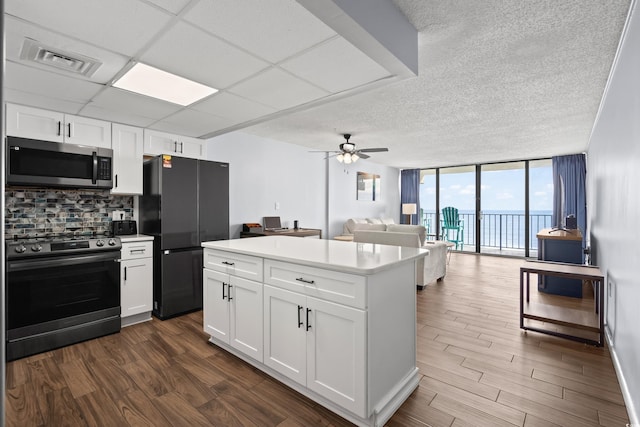 kitchen featuring visible vents, decorative backsplash, appliances with stainless steel finishes, open floor plan, and a wall of windows