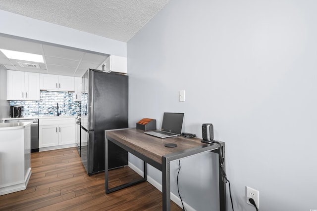 kitchen featuring tasteful backsplash, dark wood-style floors, freestanding refrigerator, white cabinetry, and a sink