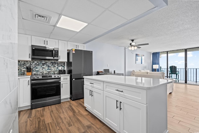 kitchen with appliances with stainless steel finishes, dark wood-style flooring, backsplash, and floor to ceiling windows