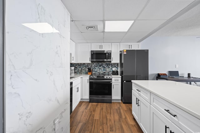 kitchen featuring stainless steel appliances, dark wood-type flooring, a paneled ceiling, and white cabinetry