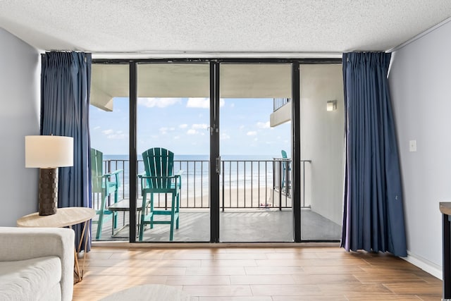 doorway to outside with expansive windows, a textured ceiling, plenty of natural light, and wood finished floors