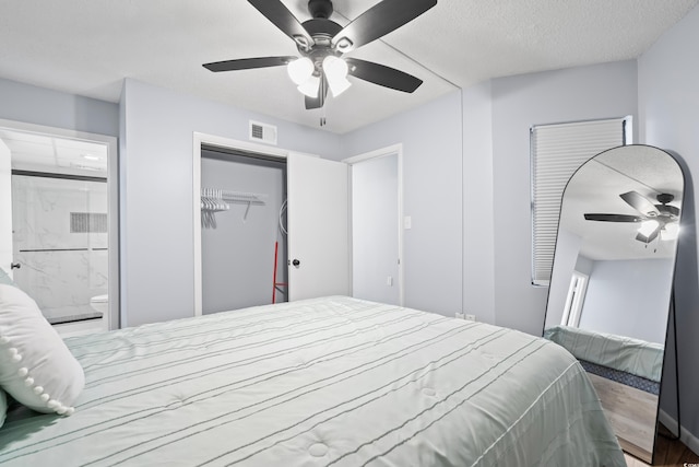 bedroom with a textured ceiling, ceiling fan, connected bathroom, visible vents, and a closet