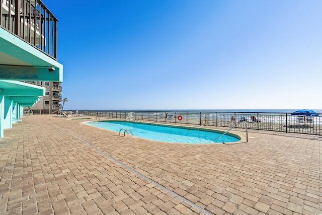 pool featuring a water view and a patio area