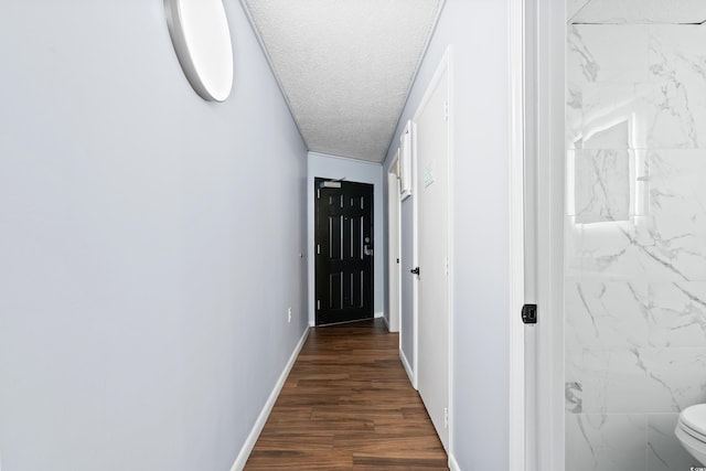 hallway with a textured ceiling, dark wood-type flooring, and baseboards