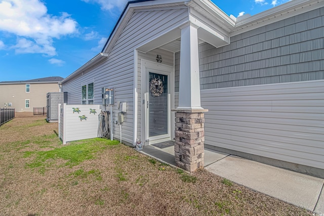 view of exterior entry featuring a lawn