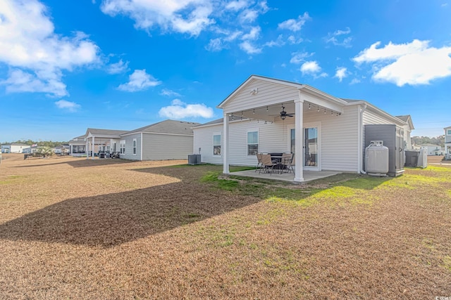 rear view of house with central AC unit, ceiling fan, a patio area, and a yard