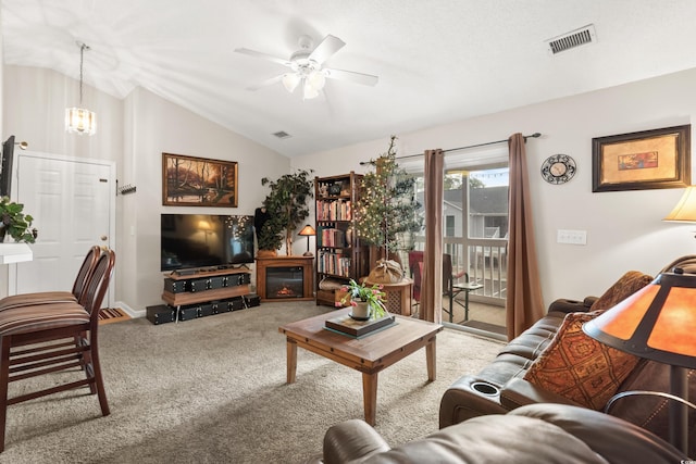 carpeted living room with ceiling fan with notable chandelier and vaulted ceiling