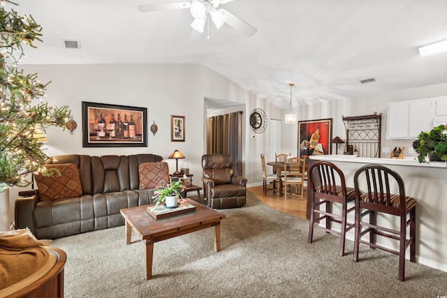 carpeted living room with ceiling fan with notable chandelier and vaulted ceiling