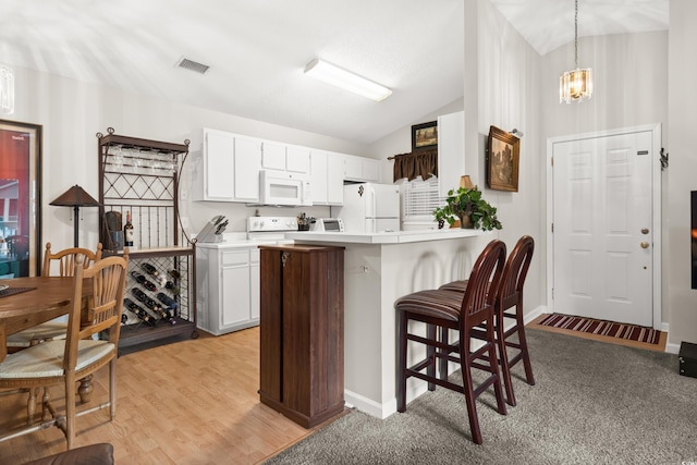 kitchen featuring white appliances, vaulted ceiling, pendant lighting, a notable chandelier, and white cabinetry