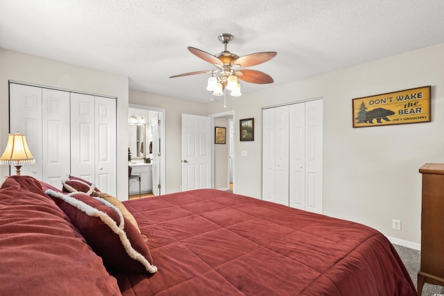 carpeted bedroom featuring ceiling fan, a textured ceiling, connected bathroom, and two closets