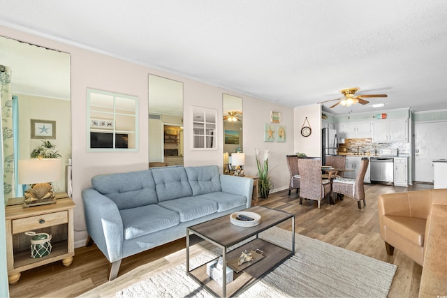 living room with light hardwood / wood-style floors, ceiling fan, and ornamental molding