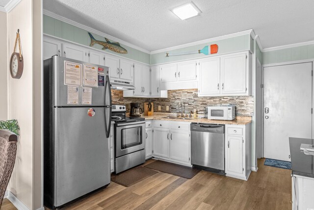 kitchen featuring white cabinetry, stainless steel appliances, a textured ceiling, and ornamental molding