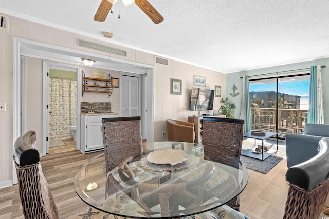 dining room featuring ceiling fan, light hardwood / wood-style flooring, crown molding, and a textured ceiling