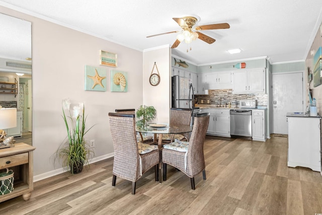 dining area with ceiling fan, light wood-type flooring, and ornamental molding