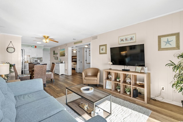 living room with hardwood / wood-style flooring, ceiling fan, and crown molding