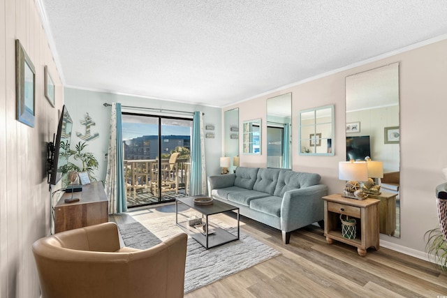 living room featuring light wood-type flooring, a textured ceiling, and ornamental molding