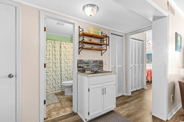 kitchen with sink, crown molding, hardwood / wood-style floors, decorative backsplash, and white cabinets