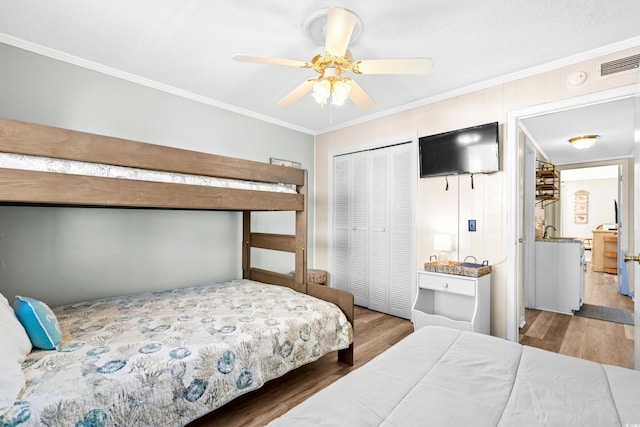 bedroom featuring hardwood / wood-style flooring, ceiling fan, ornamental molding, and a closet