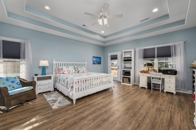 bedroom with ceiling fan, dark hardwood / wood-style floors, and a tray ceiling