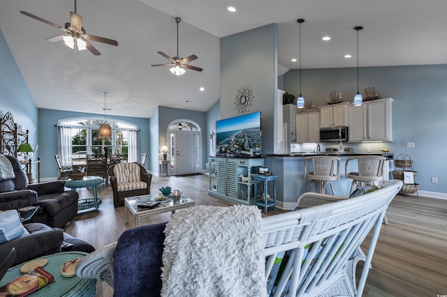 living room with ceiling fan, high vaulted ceiling, and light wood-type flooring