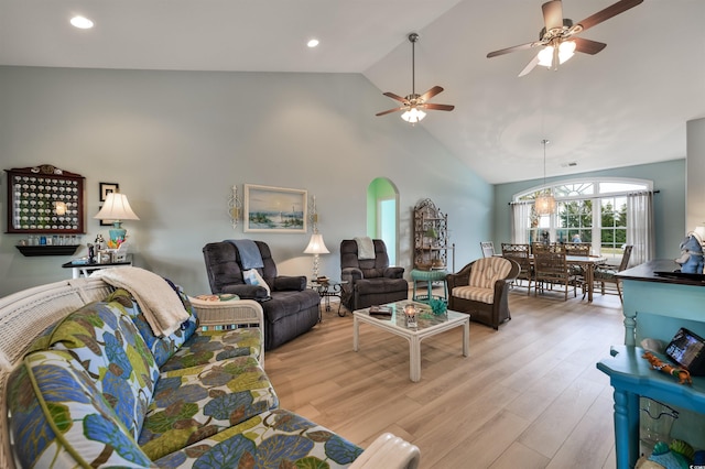 living room featuring ceiling fan with notable chandelier, lofted ceiling, and light wood-type flooring