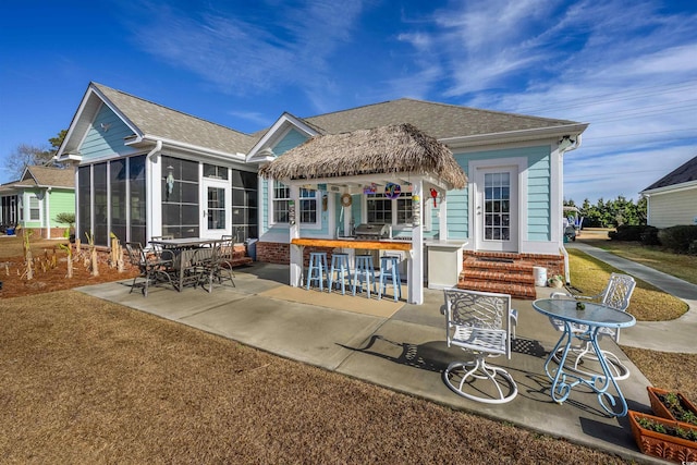 rear view of property with a patio area, a sunroom, and a bar