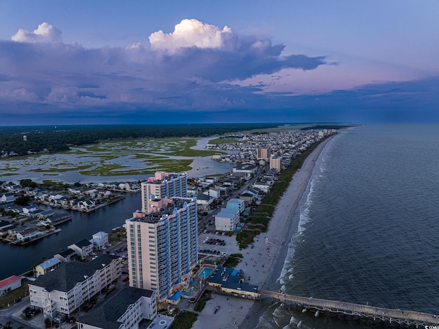 aerial view at dusk with a water view and a view of the beach