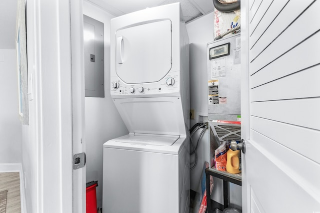 washroom with electric panel, stacked washer and dryer, and light hardwood / wood-style floors