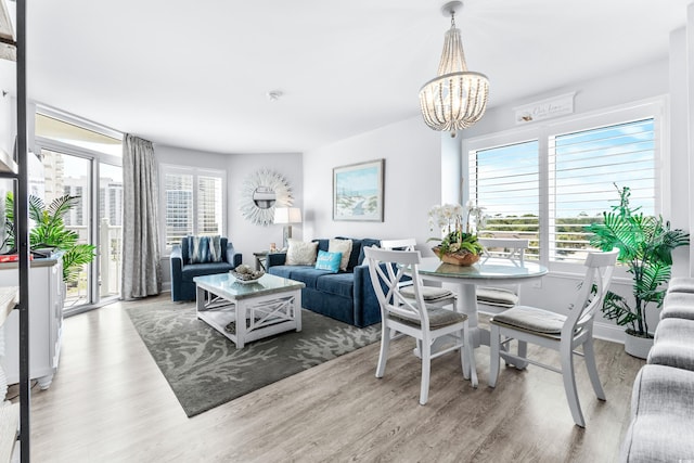 dining space with a wealth of natural light, a notable chandelier, and light wood-type flooring