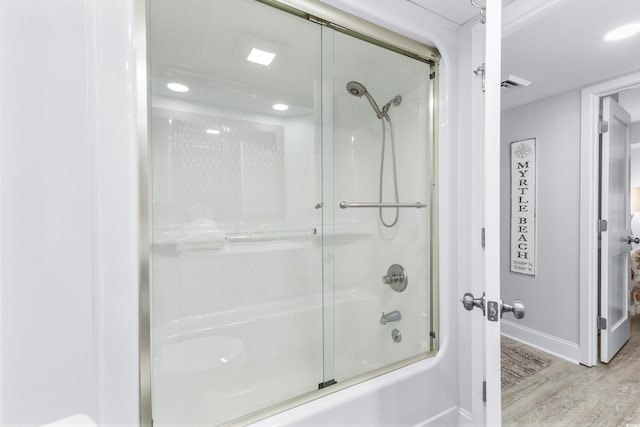 bathroom featuring hardwood / wood-style floors and bath / shower combo with glass door