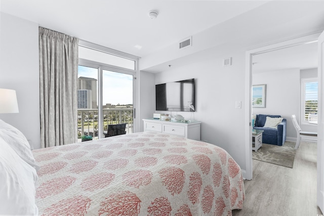 bedroom with access to exterior, light wood-type flooring, and multiple windows