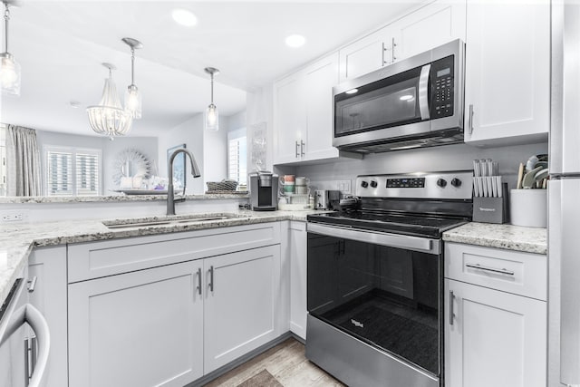 kitchen with pendant lighting, white cabinetry, sink, and appliances with stainless steel finishes