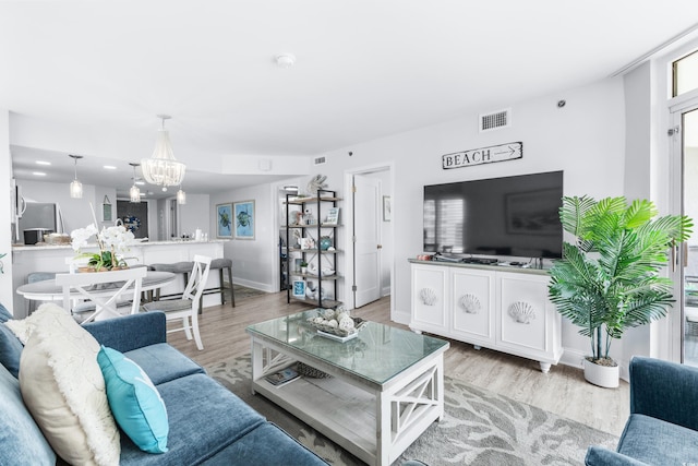 living room with a notable chandelier and light wood-type flooring