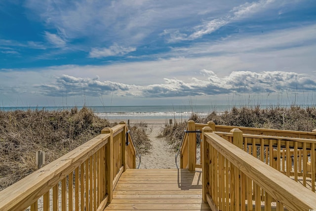 view of property's community featuring a deck with water view and a view of the beach