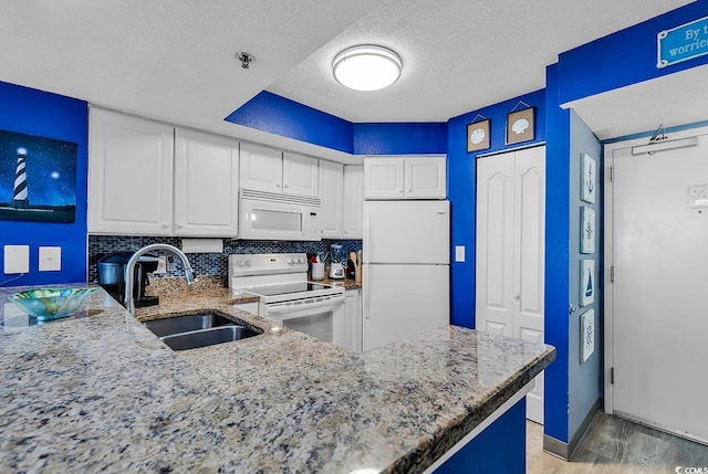 kitchen with sink, white cabinetry, tasteful backsplash, kitchen peninsula, and white appliances