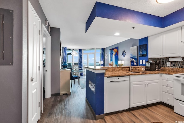 kitchen with sink, white appliances, white cabinetry, decorative backsplash, and kitchen peninsula