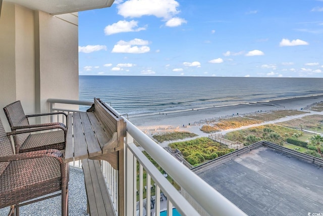 balcony with a water view and a view of the beach