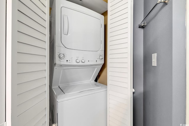 clothes washing area with stacked washing maching and dryer