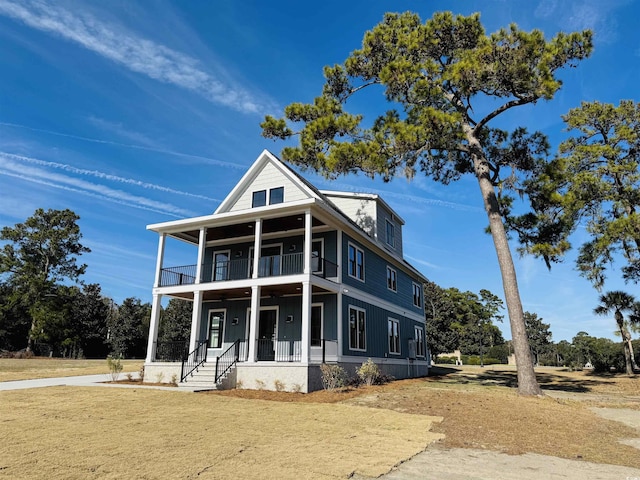 view of front of house featuring covered porch, a balcony, and a front lawn