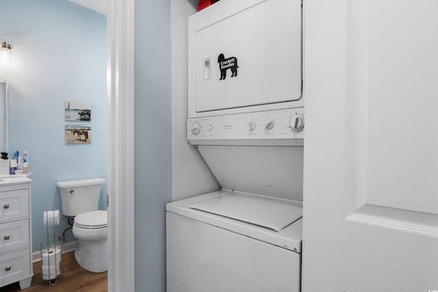 clothes washing area with wood-type flooring and stacked washer and dryer