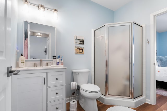 bathroom featuring vanity, hardwood / wood-style flooring, toilet, and a shower with door