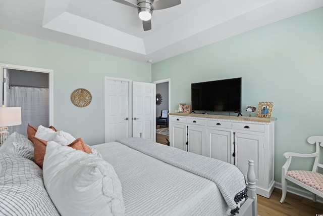 bedroom featuring a tray ceiling, light hardwood / wood-style flooring, and ceiling fan