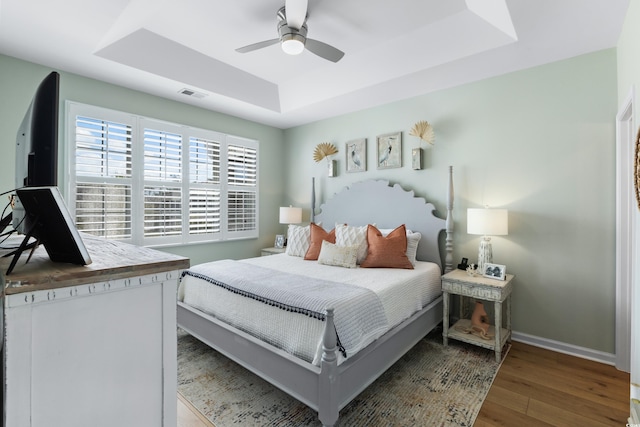 bedroom featuring a tray ceiling, ceiling fan, and wood-type flooring