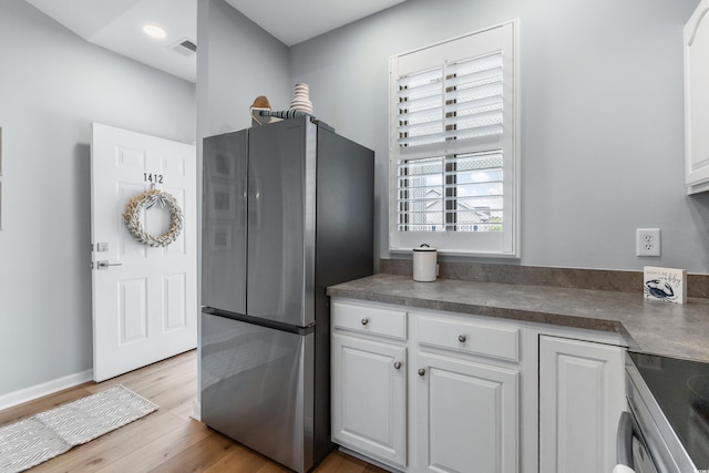 kitchen with stainless steel refrigerator, white cabinetry, stove, and light hardwood / wood-style floors