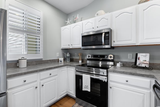 kitchen with stainless steel appliances, white cabinetry, and dark hardwood / wood-style floors